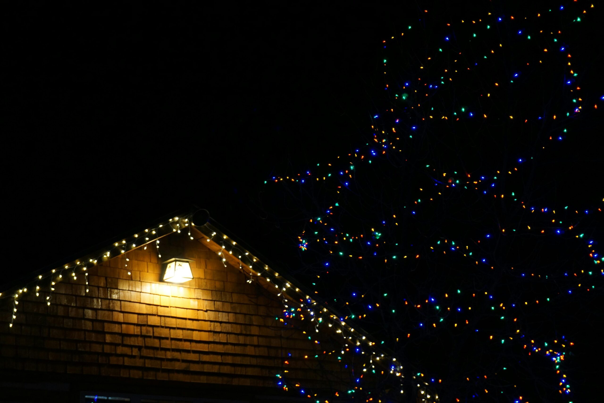 A cozy house illuminated by colorful string lights, creating a festive night scene.
