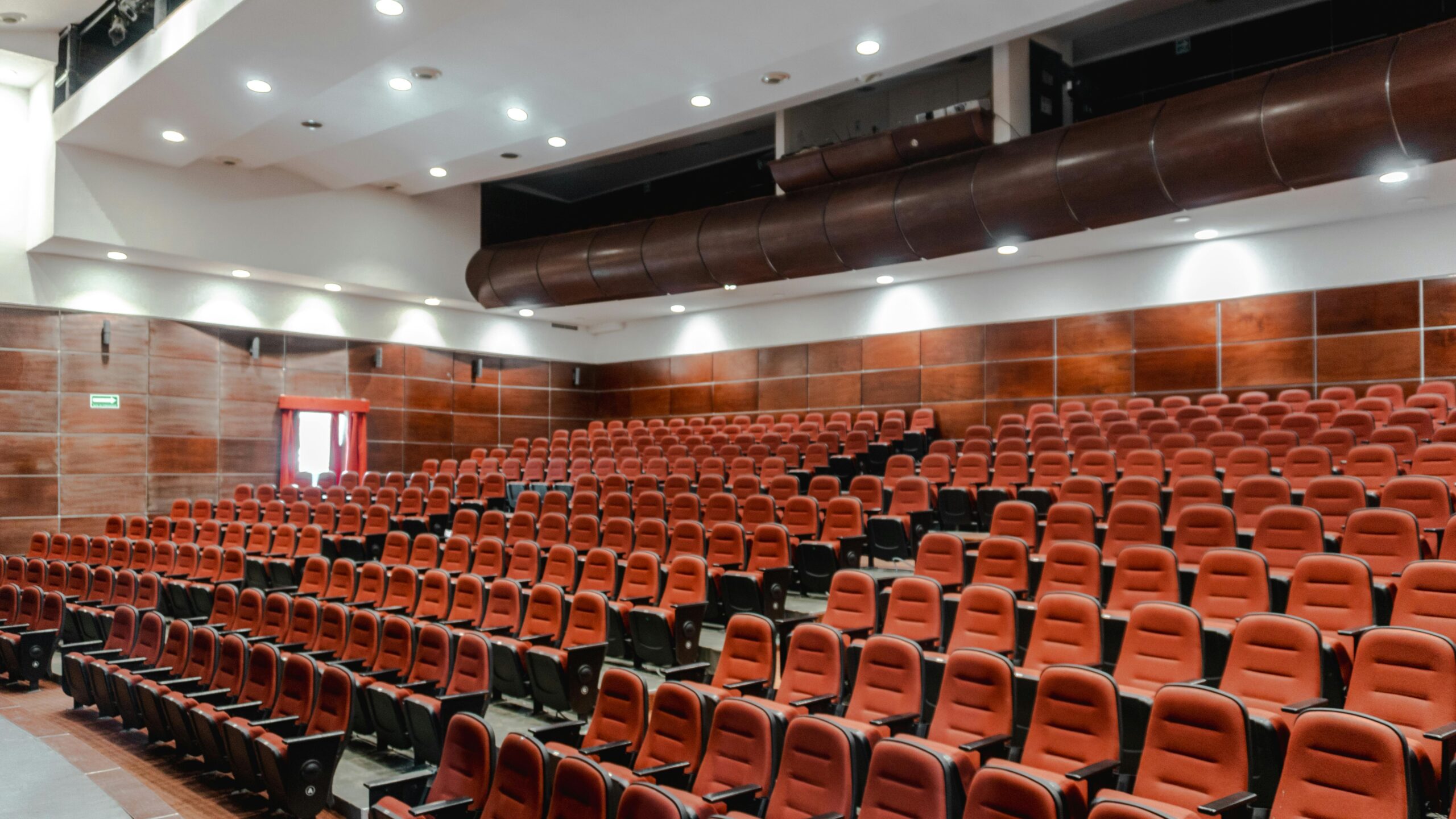 Contemporary auditorium interior with red seating and sleek design.